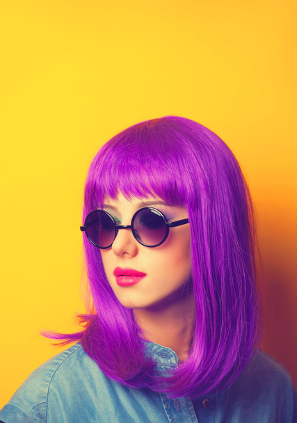 όμορφη κοπέλα με μοβ μαλλιά σε γυαλιά ηλίου σε κίτρινο φόντο - Φωτογραφία, εικόνα