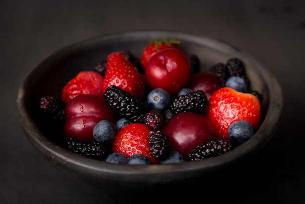 plate of fresh plums, blackberries, strawberries, blueberries on - Фото, изображение