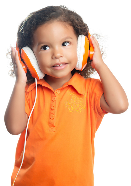 Lttle girl with an afro hairstyle enjoying her music on bright orange headphones - Foto, imagen