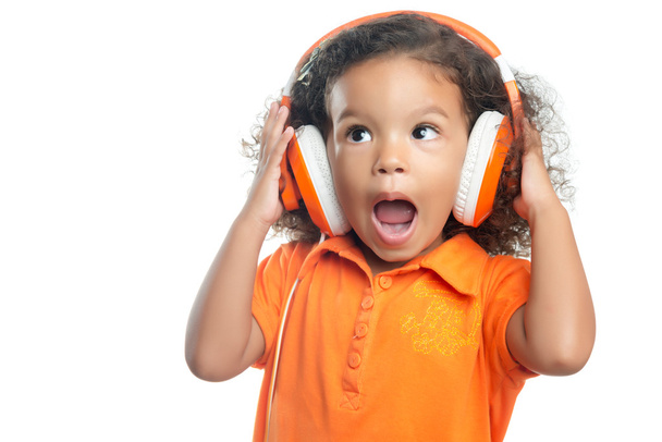 Excited little girl with an afro hairstyle enjoying her music on bright orange headphones - Fotografie, Obrázek