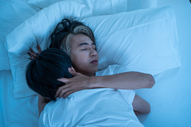 Asian attractive male LQBTQ starting foreplay and making love at home. Handsome romantic man gay couple spending leisure time together having sex in dark night room in house. Homosexual-LGBTQ concept. - Фото, изображение