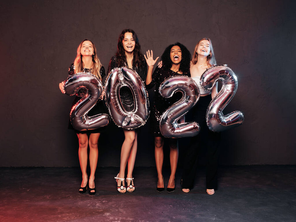 Beautiful Women Celebrating New Year.Happy Gorgeous Female In Stylish Sexy Party Dresses Holding Silver 2022 Balloons, Having Fun At New Year's Eve Party. Holiday Celebration.Charming Models  - Foto, imagen