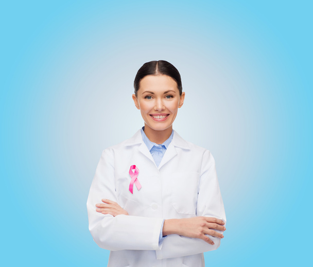 smiling female doctor with cancer awareness ribbon - Foto, afbeelding