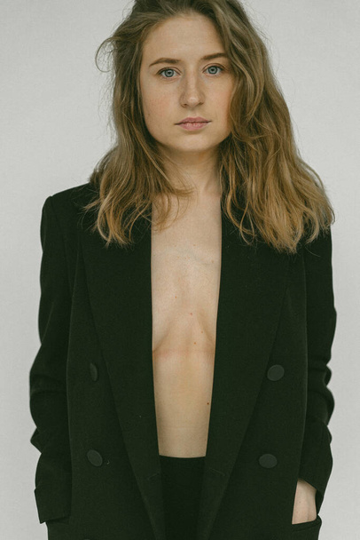 Young beautiful blonde woman in a jacket on a naked body. Studio - Foto, afbeelding