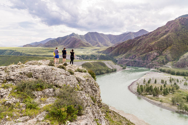Una familia admira el río de montaña mientras se encuentra en una orilla empinada en la confluencia de los ríos Katun y Chuya. - Foto, Imagen