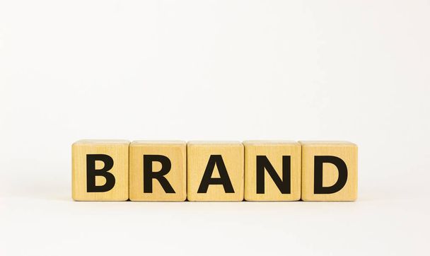 Brand symbol. The concept word 'brand' on wooden cubes on a beautiful white table, white background. Business and brand concept. Copy space. - 写真・画像