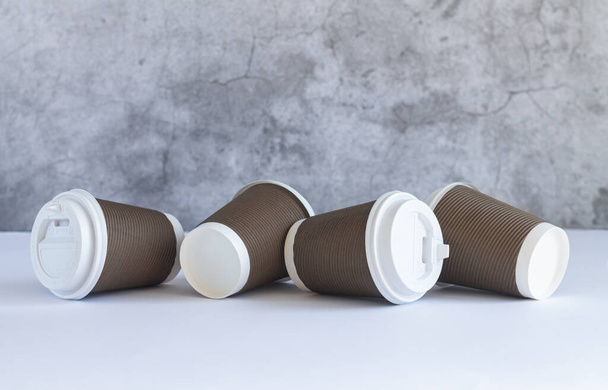 Vier bruine wegwerp papieren koffiebeker met witte kapjes op houten tafel. Afhaaldrank en milieuvriendelijk servies concept - Foto, afbeelding