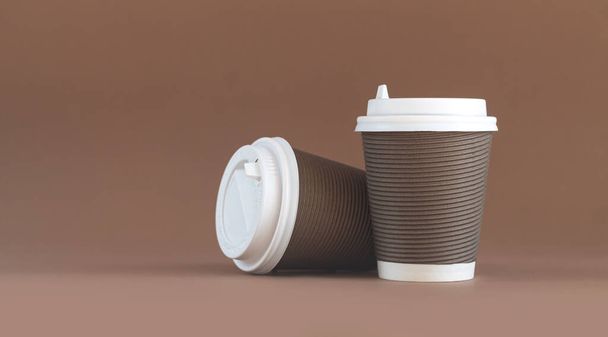 Banner από δύο χάρτινα κυματοειδή φλιτζάνια καφέ με καπάκια σε καφέ φόντο με αντιγραφικό χώρο - Φωτογραφία, εικόνα
