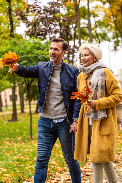 Portrait of an adult couple in love. Handsome man and a beautiful woman having fun together walking  in the sunny park. Autumn toned image - Фото, зображення
