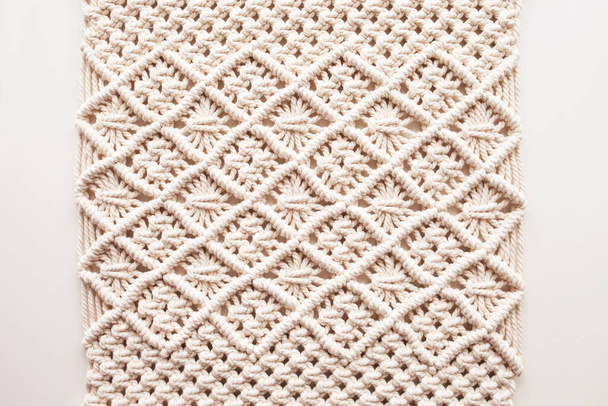 Handmade macrame. Macrame braiding and cotton threads.  Female hobby.  ECO friendly modern knitting DIY natural decoration concept in the interior.  100% cotton wall decoration.  - Foto, afbeelding