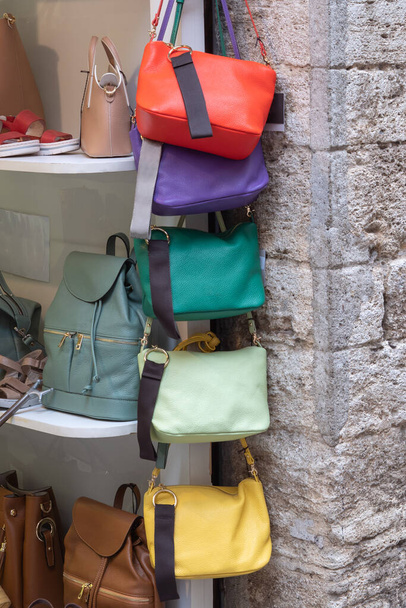 Πολύχρωμες δερμάτινες τσάντες κρέμονται στη στήλη έξω από ένα κατάστημα πολυτελείας στην Ιταλία. - Φωτογραφία, εικόνα