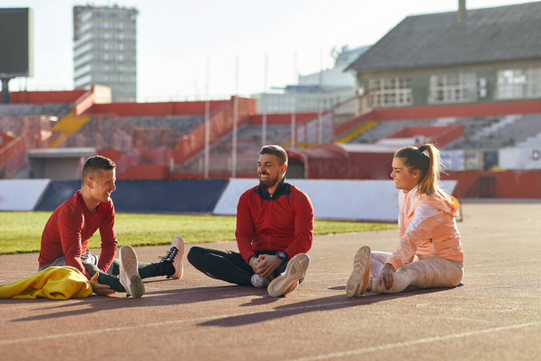 Group of three athletes stretching together at the practice - Foto, afbeelding