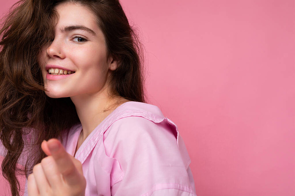 Ritratto di bella felice sorridente positivo giovane donna bruna riccia indossa camicia rosa e cappello grigio isolato su sfondo rosa con spazio copia - Foto, immagini