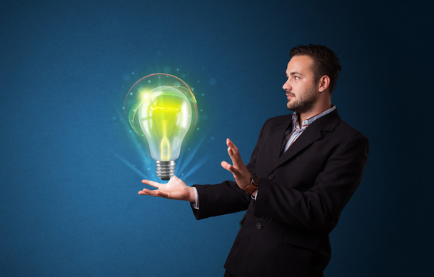 Glowing lightbulb in the hand of a businessman - Fotó, kép