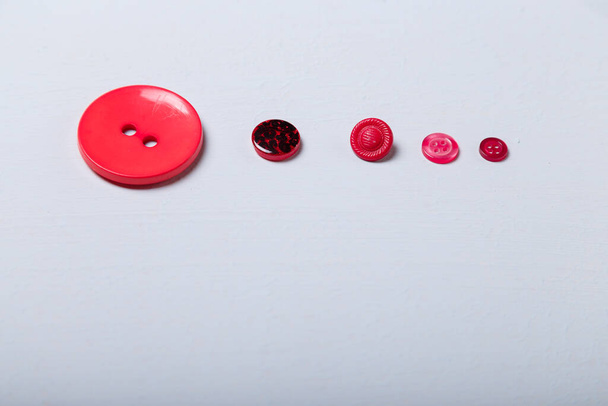 Different red buttons on white background arranged to size from big to small - Valokuva, kuva