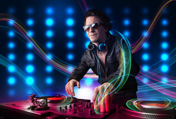 Young Dj mixing records with colorful lights - Photo, Image