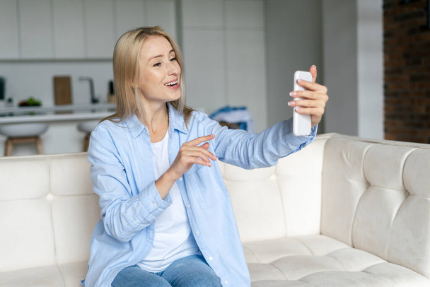 楽しさとフレンドリーな女性は、彼女のスマートフォンでウェブカメラを見て、インターネットを介して友人や家族と話すためのオンラインアプリケーションを使用して、ビデオ通話を行う。無線技術の概念 - 写真・画像