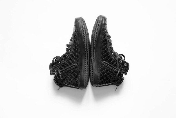 μαύρη πατέντα γυναικεία παπούτσια σχισμένα βρίσκεται σε ένα λευκό απομονωμένο φόντο, τρύπες - Φωτογραφία, εικόνα