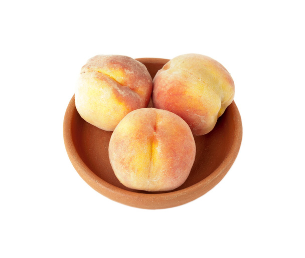 drei reife Pfirsiche in Tonteller isoliert über weißem Hintergrund - Foto, Bild