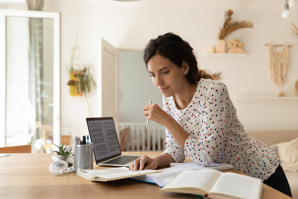 Focused adult female student doing homework, reading books at laptop - Fotografie, Obrázek