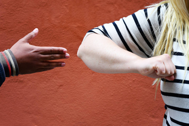 Concept of confusion of how to do greetings in the new normal after the coronavirus pandemic: say hello by shaking hands or will we do an elbow bump? Photo of a handshake and elbow bump. - Photo, Image