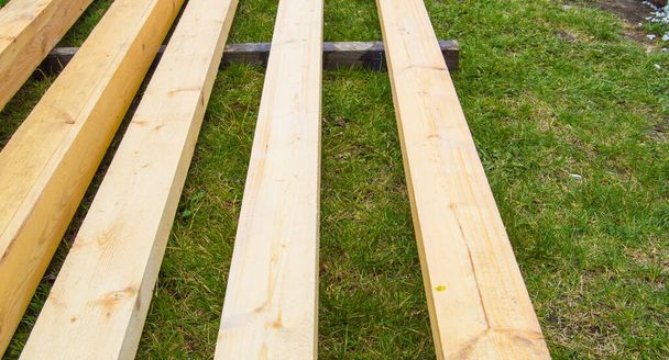 Nowe drewniane deski na trawie. Drewno do budowy podmiejskiej. - Zdjęcie, obraz