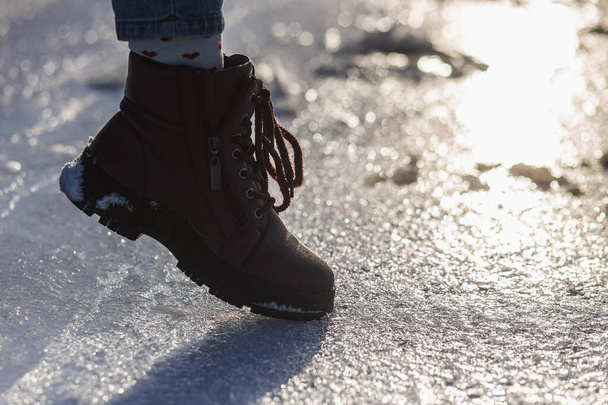 Winter is coming. Closeup Female boots on a sparkling ice crystals on the sun - Photo, Image