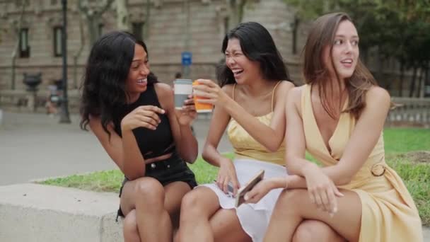 Tre gioiosi felici ragazze di razza mista bere portare via il caffè e ridere all'aperto - Filmati, video