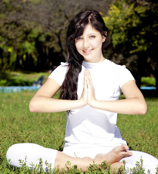 Beautiful young brunet yoga girl on green grass in park. - Photo, Image