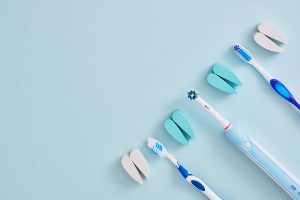 electric and plastic toothbrushes on a blue background, which brushes are more effective in cleaning the oral cavity and more eco-friendly - Fotoğraf, Görsel