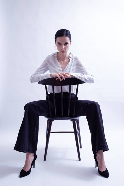woman in white shirt and black trousers sits on a chair - Фото, зображення