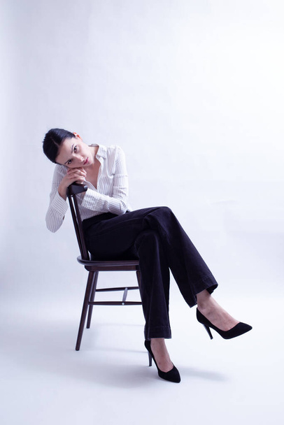 donna in camicia bianca e pantaloni neri seduta su una sedia - Foto, immagini