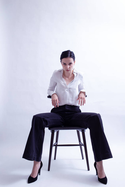 woman in white shirt and black trousers sits on a chair - Foto, Imagem