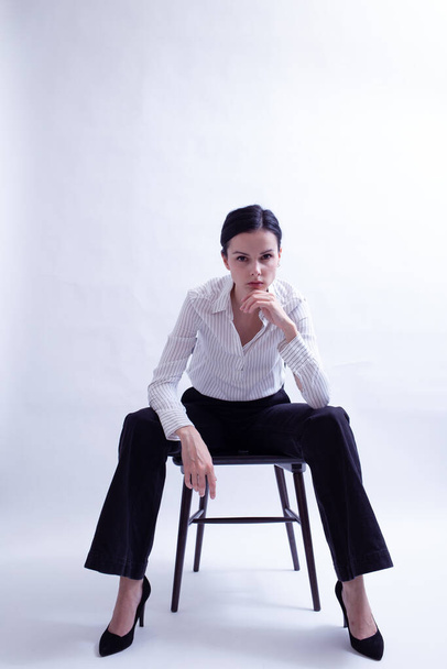 woman in white shirt and black trousers sits on a chair - Фото, зображення