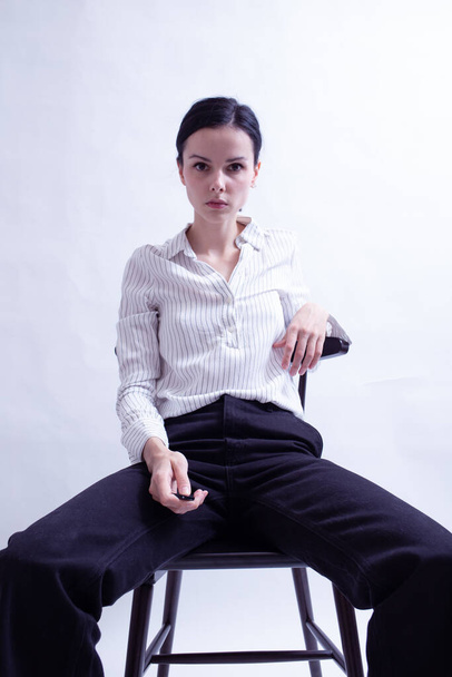 woman in white shirt and black trousers sits on a chair - Fotografie, Obrázek