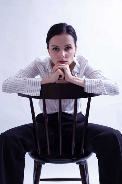 woman in white shirt and black trousers sits on a chair - Fotografie, Obrázek