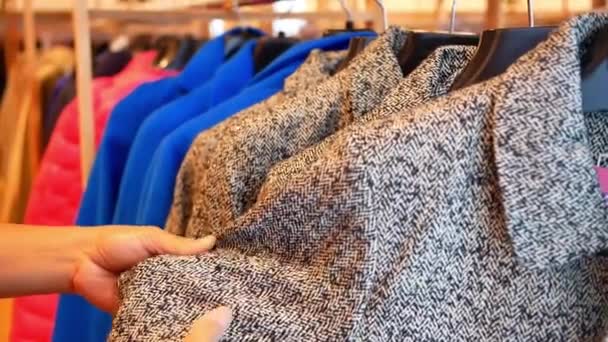 Vrouwelijke handen kiezen winterkleding op hanger in een kledingwinkel. - Video