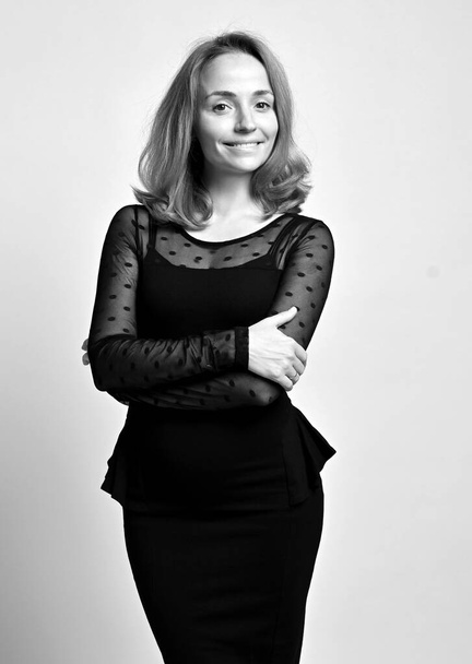 Zwart-wit portret van vriendelijke slanke vrouw kantoormedewerker in zwart formele strakke jurk of kant blouse en strakke rok - Foto, afbeelding