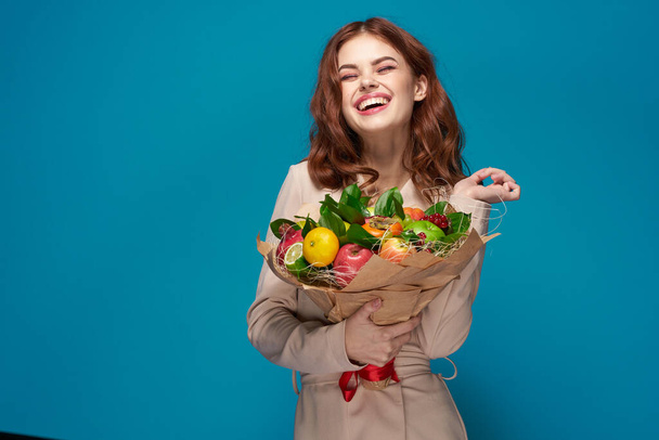 pretty woman beige coat fruit bouquet in hands isolated background - Valokuva, kuva