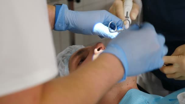 Operação cirúrgica na odontologia moderna. Dentistas que realizam tratamento cirúrgico instalando implantes dentários ou extraindo dente ruim. Os médicos usam roupas de proteção e luvas trabalhando no paciente dental - Filmagem, Vídeo