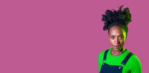 Portrait young black woman posing isolated staring friendly and relaxed smiling positive on pink advertising copyspace background - Fotografie, Obrázek