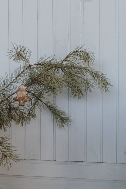 Spar, spar naalden versierd met kerstspeelgoed in de voorkant van witte houten muur. Minimalistische kerst, Nieuwjaar vakantie achtergrond - Foto, afbeelding