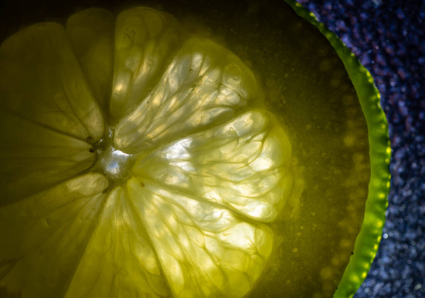 creative food art macro, partially illuminated lemon and lime fruit sclices on textured background - Photo, Image