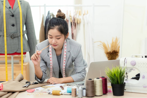 Work from home. Asian young woman fashion designer  working on her design in the showroom.  Lifestyle people Stylish tailor taking measurements on mannequin in studio.  Business small Concept - Fotó, kép