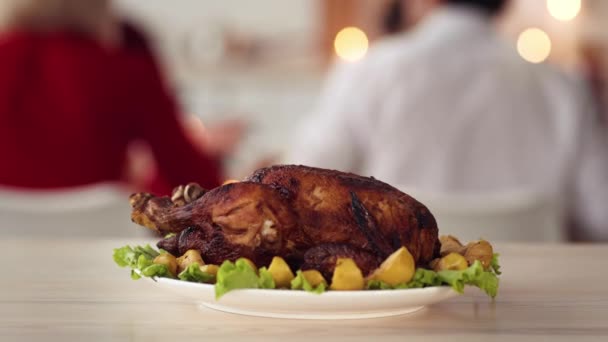 Plat de dinde rôti sur fond avec la famille célébrant Thanksgiving à l'intérieur - Séquence, vidéo