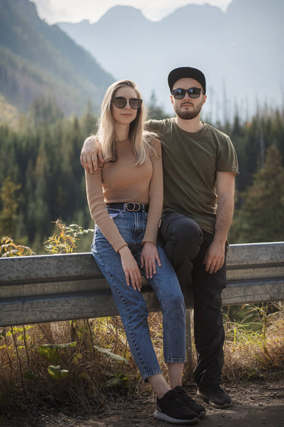 Νεαρό ζευγάρι τουριστών, άνδρας και γυναίκα, στο μονοπάτι της πεζοπορίας στα βουνά την ηλιόλουστη μέρα - Φωτογραφία, εικόνα