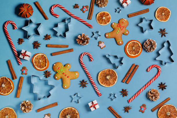 Christmas food background. Gingerbread cookies, candy canes spices and decorations on blue - Фото, зображення