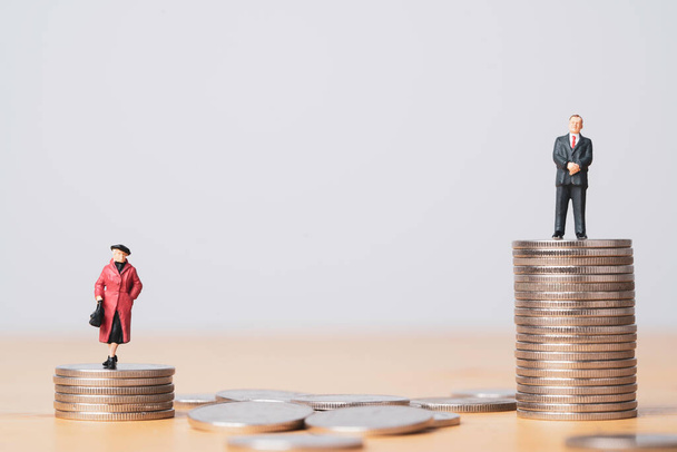 Miniature figure of businessman standing on higher than coins stacking of  businesswoman for inequality of gender male and female of income and salary concept. - Photo, Image