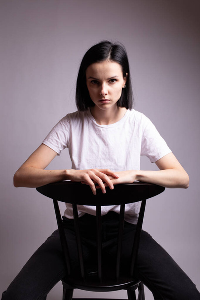 дівчина в білій футболці сидить на стільці в студії
 - Фото, зображення