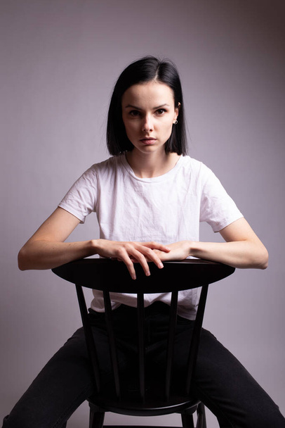 girl in a white t-shirt sits on a chair in the studio - Fotoğraf, Görsel